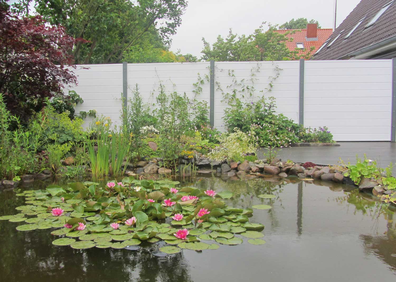 lange Sichtschutzwand in Weiß im Garten an der Grundstücksgrenze