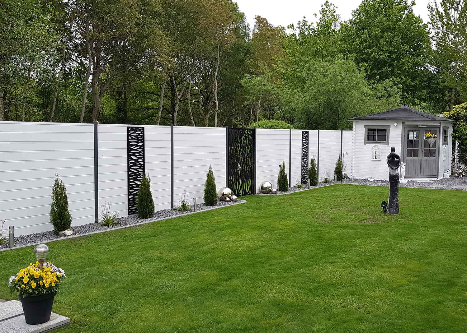 lange Sichtschutzwand in Weiß mit Steckpfosten im Garten und passenden künstlerischen Elementen