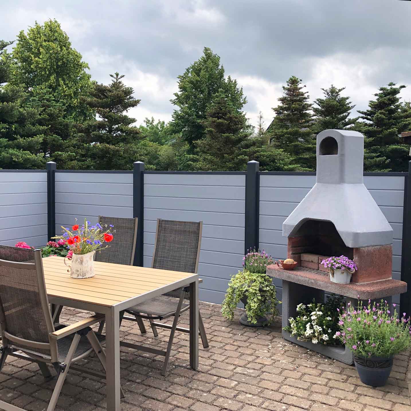 schöner Terrassensichtschutz in Grau mit Pfosten in Anthrazit an einer gemütlichen Grillecke