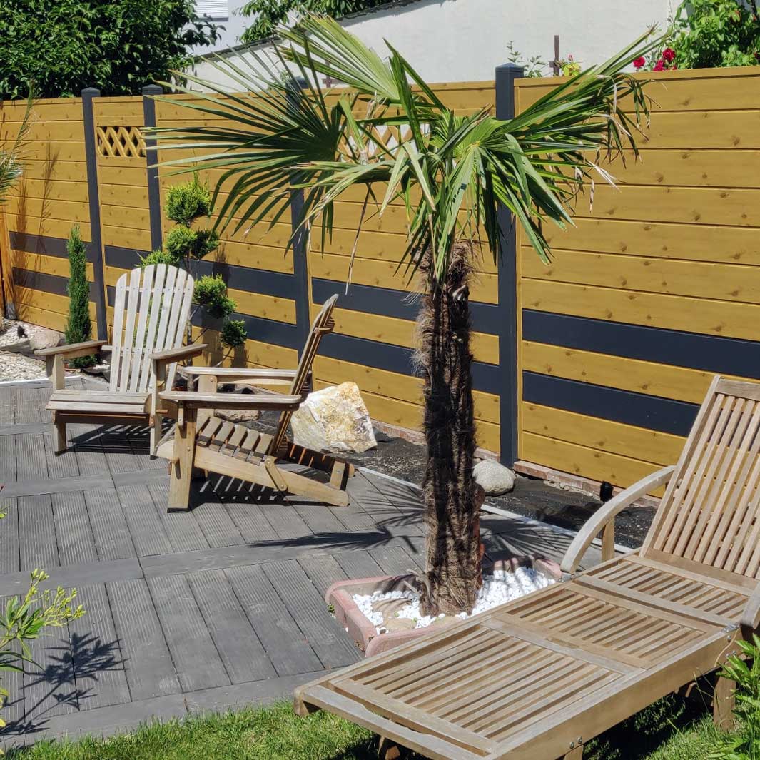 Sichtschutzzaun aus Kunststoff PVC in Astfichte und Anthrazit auf einer Sommerterrasse mit Palmen