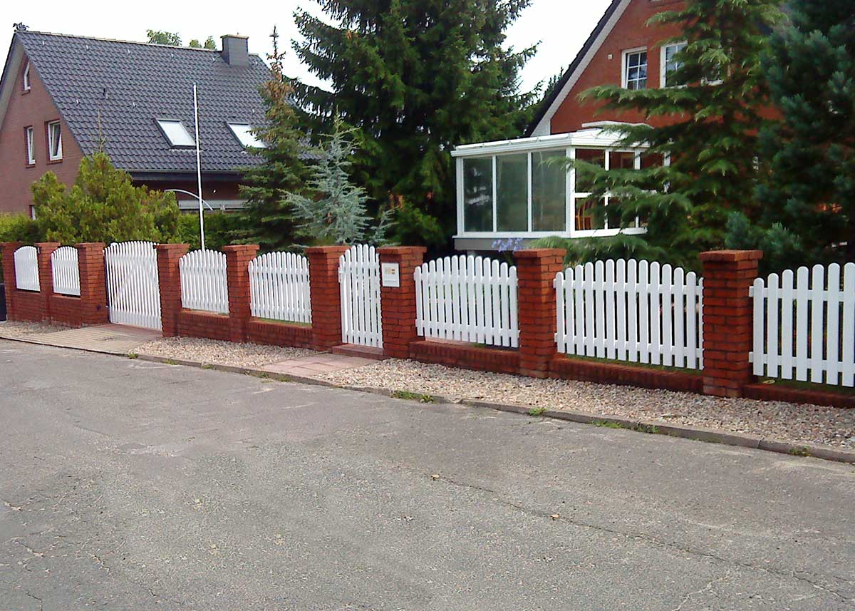 Lattenzaun Gartenzaun in Weiß aus hochwertigen Kunststoff mit Oberbogen, zwischen Ziegelmauer