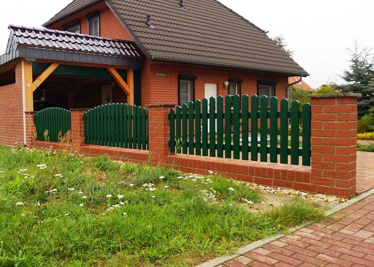 Lattenzaun Gartenzaun in Moosgrün aus hochwertigen Kunststoff mit Oberbogen, zwischen Ziegelsteinsäulen