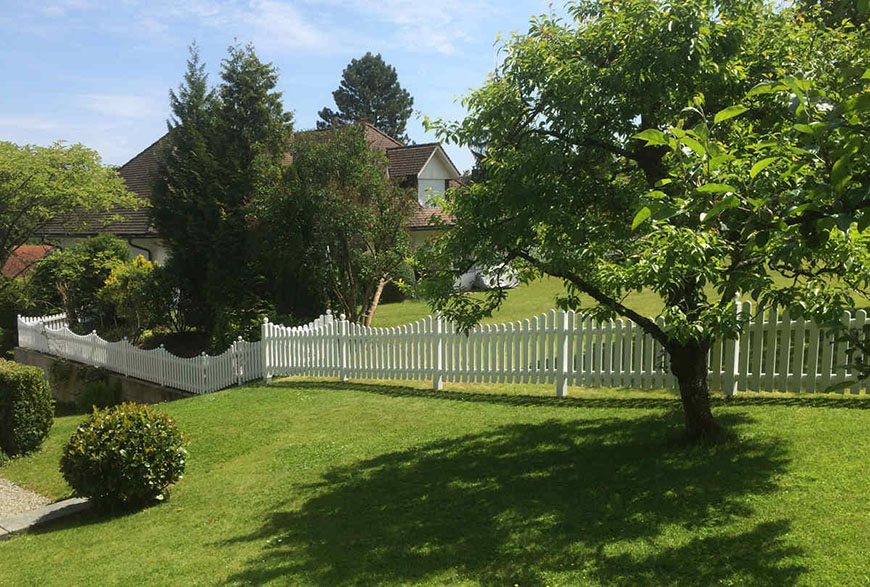 Grundstückseinfriedung weißer Gartenzaun unebenes Gelände mit Unterbogen